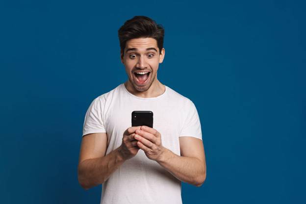 Homem de camiseta branca animado com aplicativo em seu celular