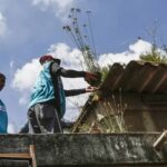 Agentes inspecionando caixa dágua em busca de focos de dengue