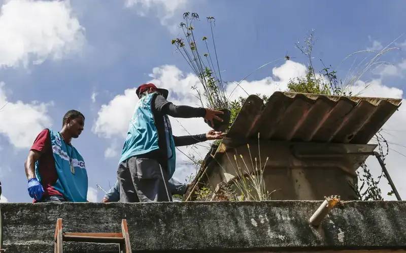 Agentes inspecionando caixa dágua em busca de focos de dengue